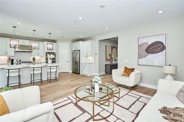 living area with recessed lighting, light wood-style flooring, and baseboards