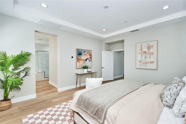 bedroom featuring light wood-type flooring, visible vents, a tray ceiling, and recessed lighting