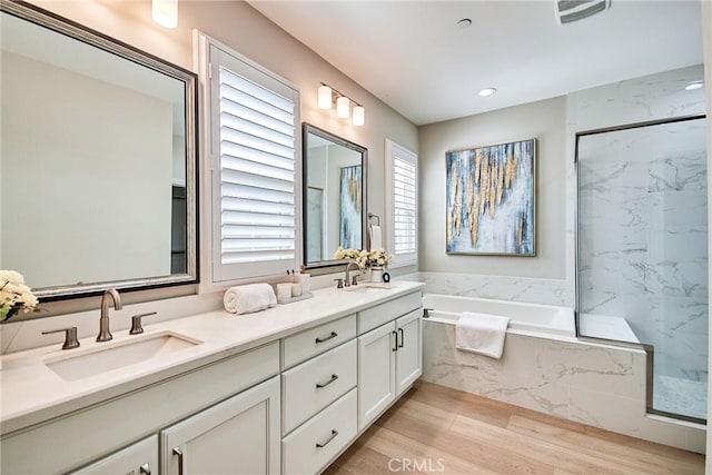 full bath featuring a bath, a marble finish shower, and a sink