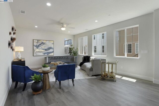 living room with wood-type flooring, ceiling fan, and a healthy amount of sunlight