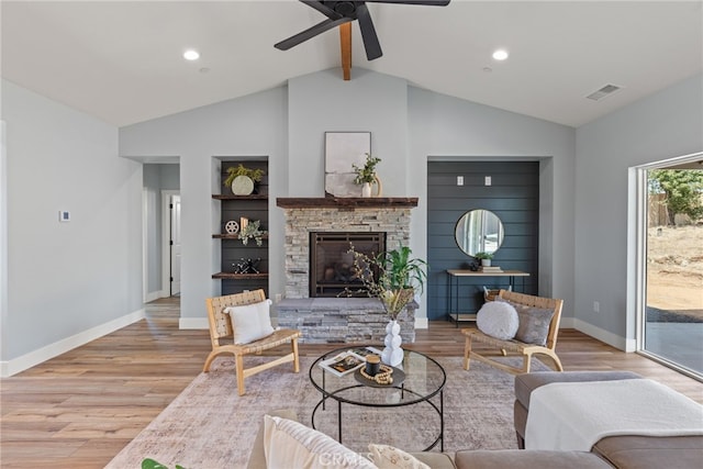 living room featuring ceiling fan, vaulted ceiling with beams, light hardwood / wood-style flooring, and a fireplace