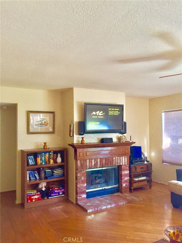 living room with hardwood / wood-style floors, a textured ceiling, and a fireplace