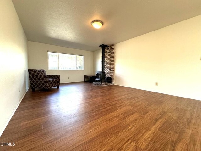 unfurnished living room featuring a wood stove and dark wood-type flooring