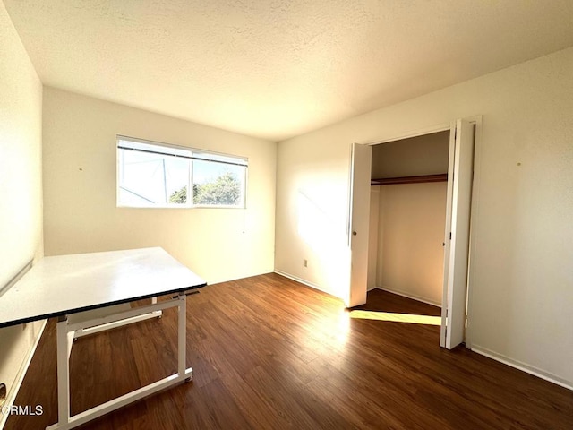 unfurnished bedroom with a closet, a textured ceiling, and dark wood-type flooring