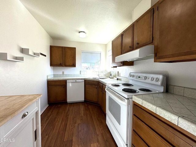 kitchen with dark hardwood / wood-style flooring, tile counters, sink, and white appliances