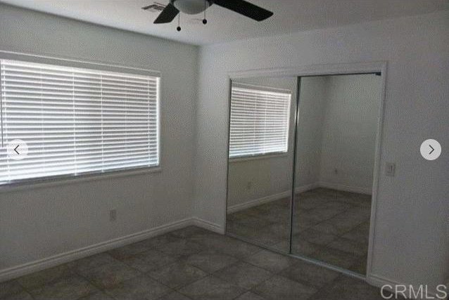 unfurnished bedroom with ceiling fan, dark tile patterned flooring, and a closet