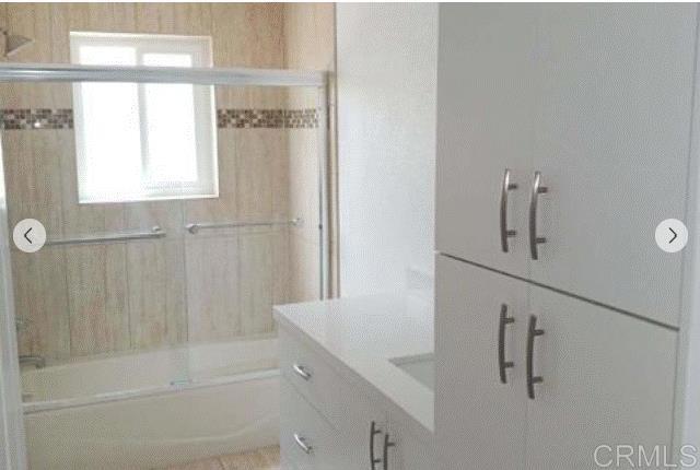 bathroom with vanity and enclosed tub / shower combo