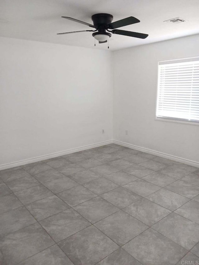 tiled empty room featuring ceiling fan