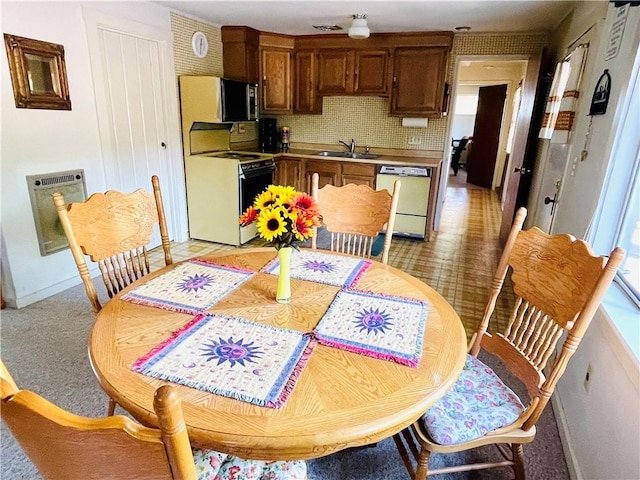 kitchen with backsplash, heating unit, sink, and white appliances