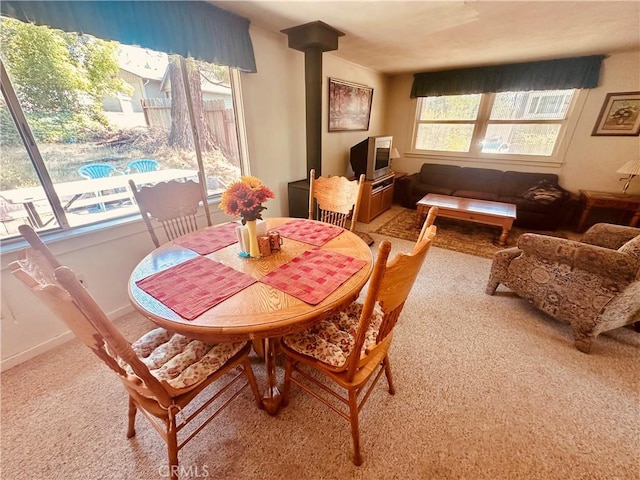 carpeted dining space with a wood stove