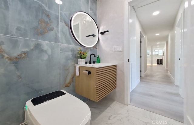 bathroom with tile walls, vanity, and toilet