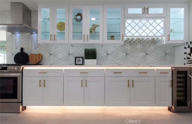 interior space featuring decorative backsplash, wall chimney exhaust hood, beverage cooler, and white cabinets