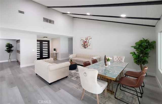 living room with beamed ceiling, light hardwood / wood-style floors, and high vaulted ceiling