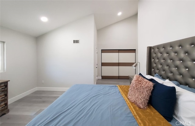 bedroom with light wood-type flooring and lofted ceiling