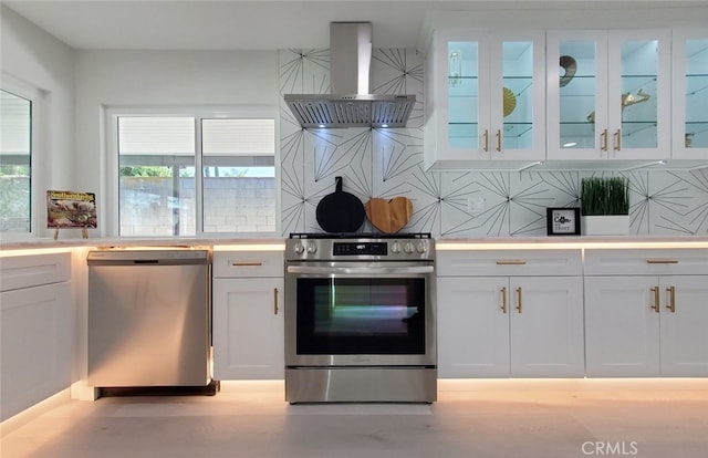 kitchen with exhaust hood, stainless steel appliances, white cabinets, and decorative backsplash