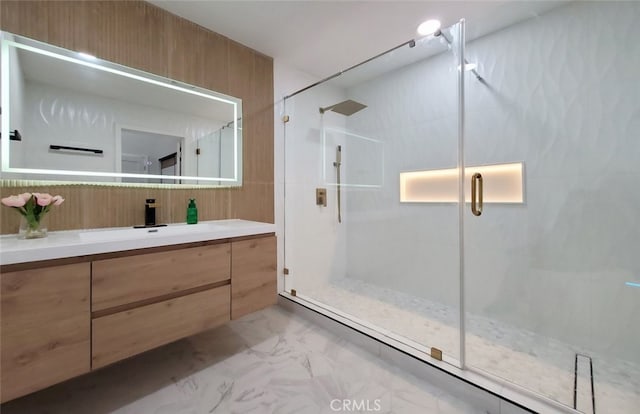 bathroom featuring a shower with shower door and vanity