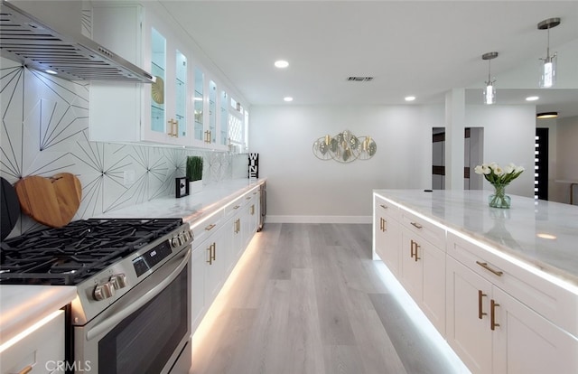 kitchen featuring light hardwood / wood-style floors, white cabinets, wall chimney exhaust hood, light stone countertops, and stainless steel range with gas cooktop