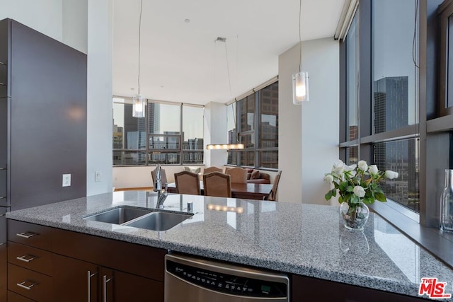 kitchen with sink, light stone counters, stainless steel dishwasher, and dark brown cabinetry