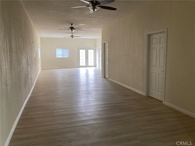 empty room with ceiling fan, hardwood / wood-style floors, and french doors