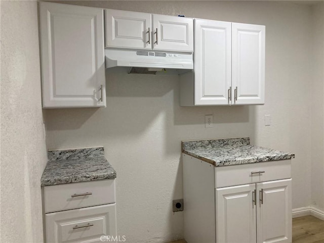 kitchen featuring white cabinetry, hardwood / wood-style floors, and light stone countertops