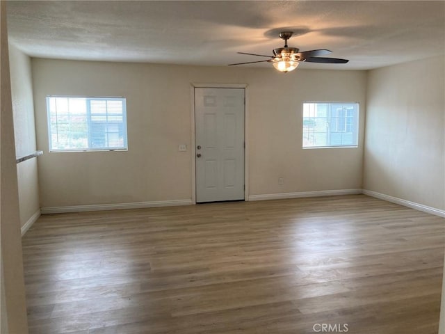 spare room with plenty of natural light, light hardwood / wood-style floors, and ceiling fan