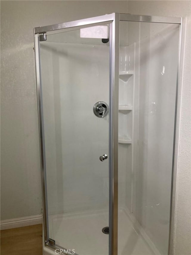 bathroom featuring a shower with shower door and wood-type flooring