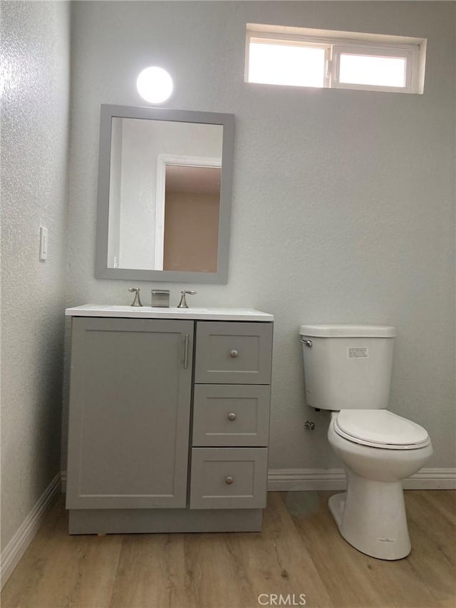 bathroom featuring plenty of natural light, vanity, hardwood / wood-style floors, and toilet