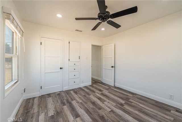 unfurnished bedroom featuring ceiling fan, dark wood-type flooring, and multiple windows