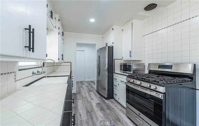 kitchen featuring white cabinets, stainless steel appliances, backsplash, and sink