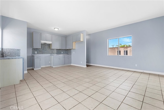 kitchen featuring decorative backsplash, exhaust hood, light tile patterned floors, and gray cabinetry