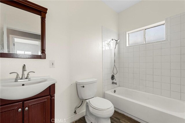 full bathroom with vanity, tiled shower / bath, wood-type flooring, and toilet