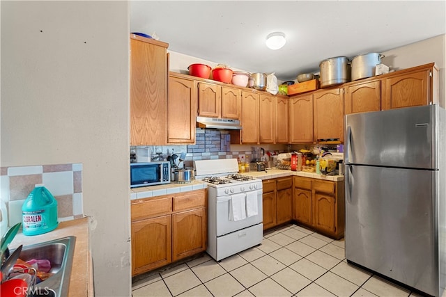 kitchen featuring sink, appliances with stainless steel finishes, light tile patterned floors, and backsplash