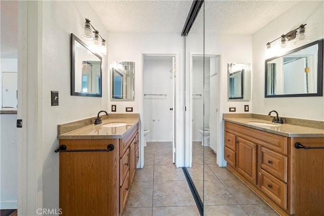 bathroom with toilet, a textured ceiling, tile patterned floors, and vanity