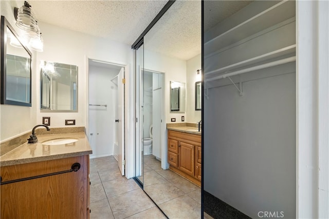 bathroom featuring a textured ceiling, toilet, tile patterned flooring, and vanity