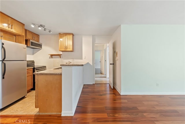 kitchen with wood-type flooring, stainless steel appliances, sink, kitchen peninsula, and light stone counters