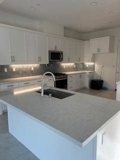 kitchen with a center island with sink, sink, white cabinets, and stainless steel appliances