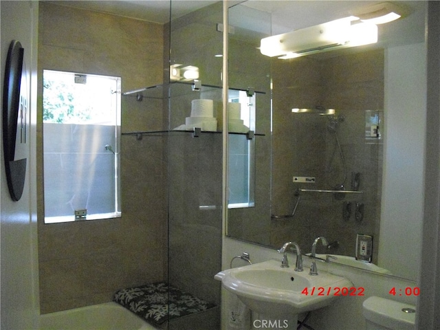 bathroom featuring toilet, sink, and an enclosed shower