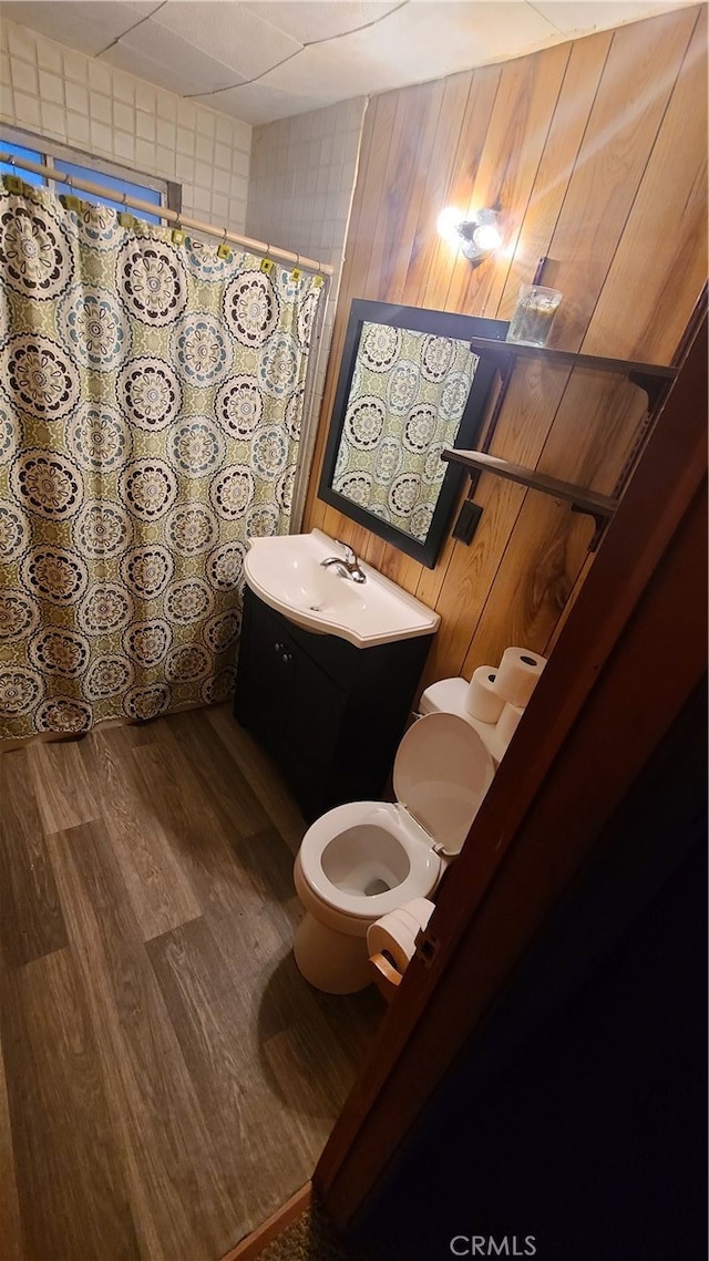 bathroom featuring wood-type flooring, toilet, wooden walls, and vanity