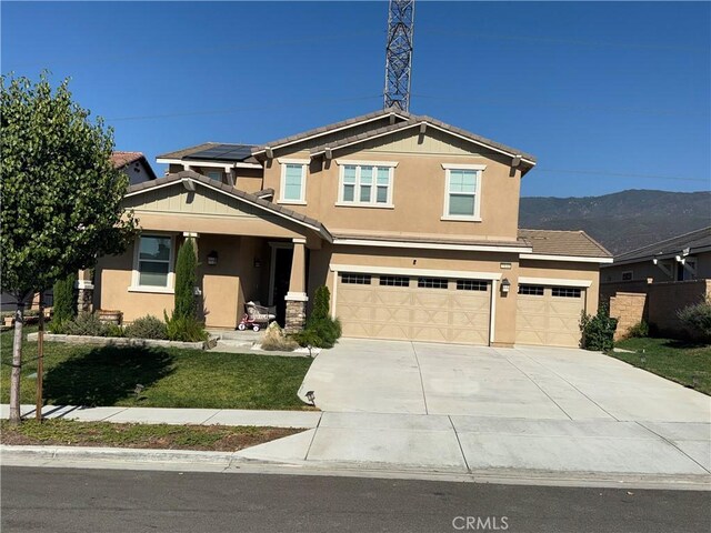 view of front of house featuring a mountain view, solar panels, a garage, and a front yard