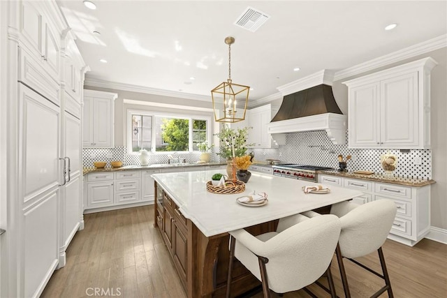 kitchen featuring custom range hood, a center island, white cabinetry, and wood-type flooring