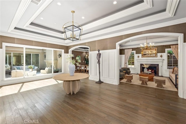 interior space featuring a raised ceiling, ornamental molding, dark hardwood / wood-style floors, and a notable chandelier