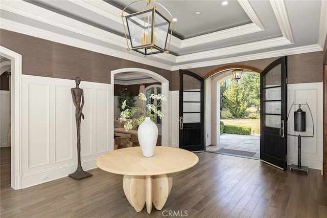 foyer entrance featuring a tray ceiling, crown molding, dark hardwood / wood-style flooring, and a chandelier