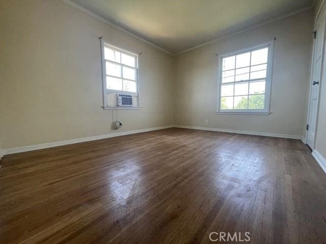 empty room with dark wood-type flooring, ornamental molding, cooling unit, and plenty of natural light