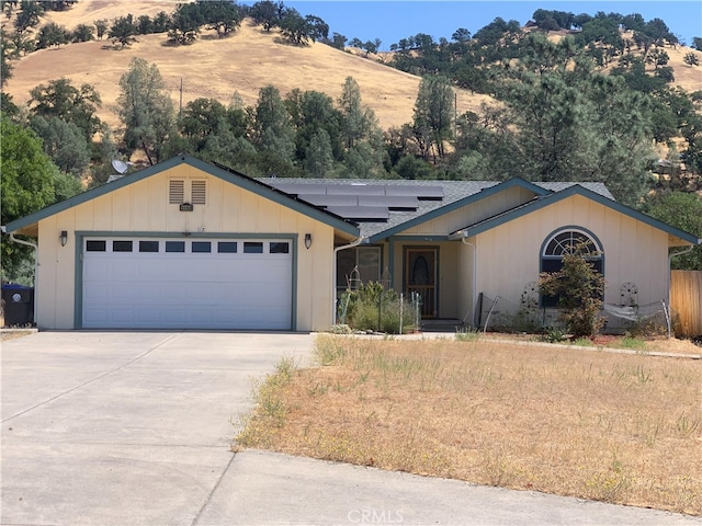 ranch-style home featuring a garage and solar panels