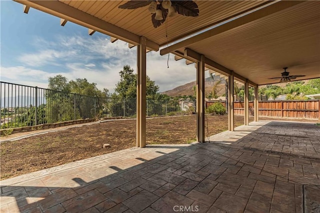 view of patio featuring a ceiling fan, a fenced backyard, and a mountain view