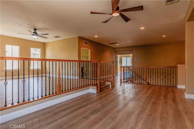 empty room with recessed lighting, wood finished floors, visible vents, and baseboards