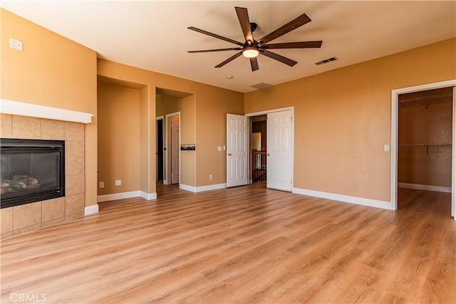 unfurnished living room with light wood finished floors, a fireplace, visible vents, and baseboards