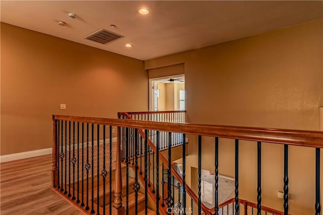 corridor with recessed lighting, wood finished floors, an upstairs landing, baseboards, and visible vents