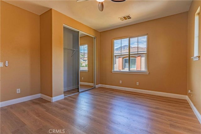 spare room featuring ceiling fan, wood finished floors, visible vents, and baseboards