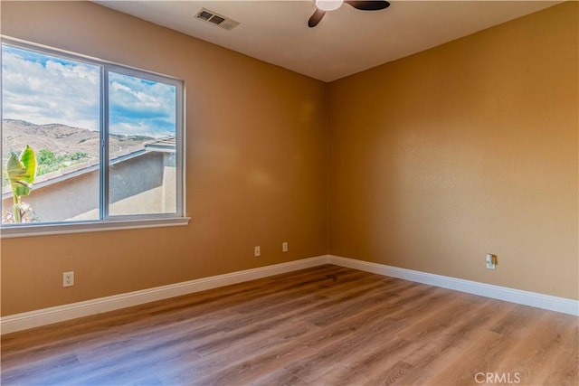 unfurnished room featuring a ceiling fan, wood finished floors, visible vents, and baseboards